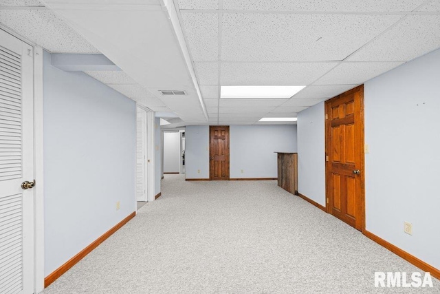 finished basement with baseboards, visible vents, carpet, and a drop ceiling