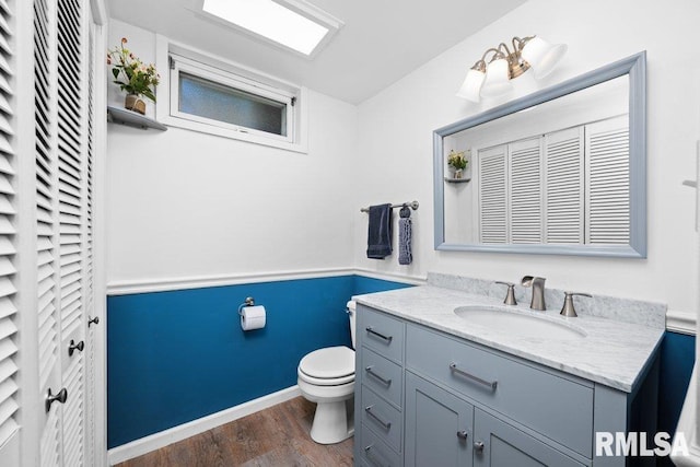 bathroom featuring toilet, vanity, and wood finished floors