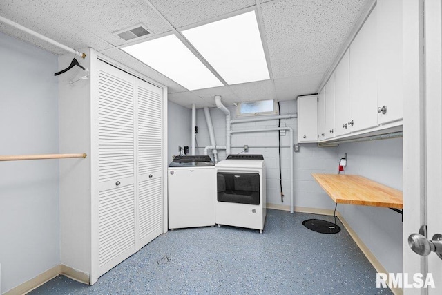 washroom featuring baseboards, visible vents, cabinet space, and washing machine and clothes dryer