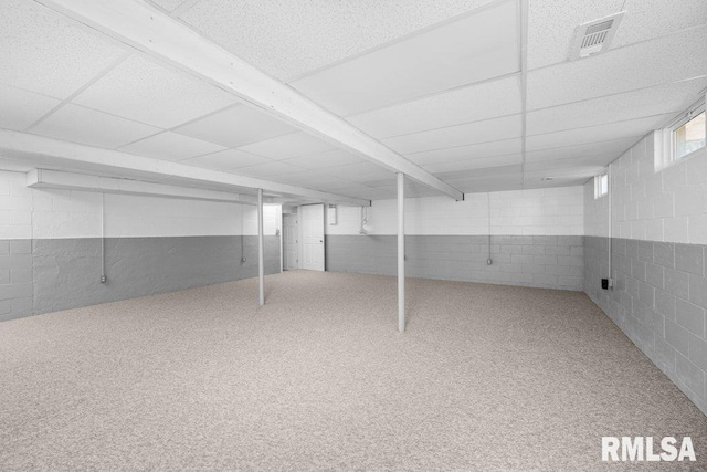 below grade area featuring visible vents, a paneled ceiling, concrete block wall, and carpet floors