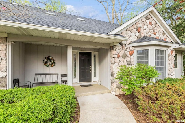 property entrance with a porch, a shingled roof, and stone siding