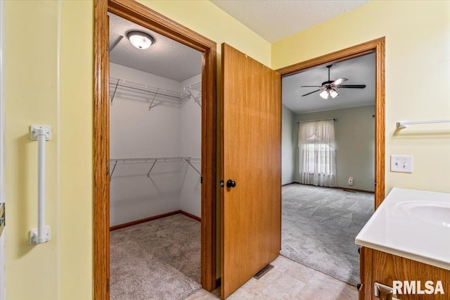 5200 Villa Dr, Davenport, IA 52806 - bathroom featuring a textured ceiling, ceiling fan, a spacious closet, and a sink