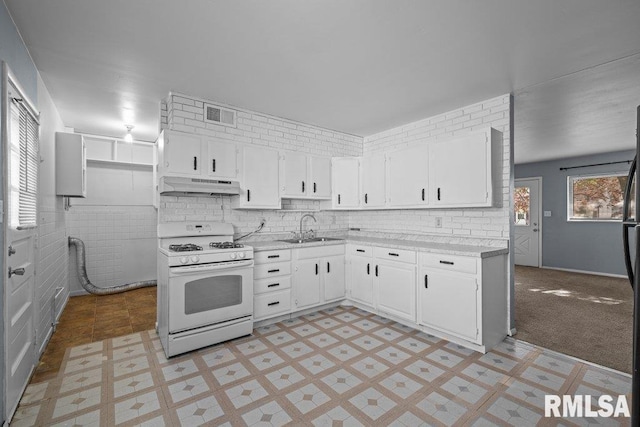 kitchen featuring gas range gas stove, a sink, under cabinet range hood, and light countertops