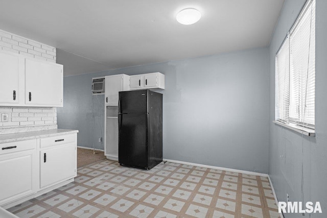 kitchen featuring white cabinets, light countertops, freestanding refrigerator, baseboards, and light floors