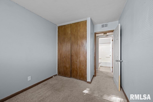 unfurnished bedroom featuring a closet, baseboards, carpet floors, and visible vents
