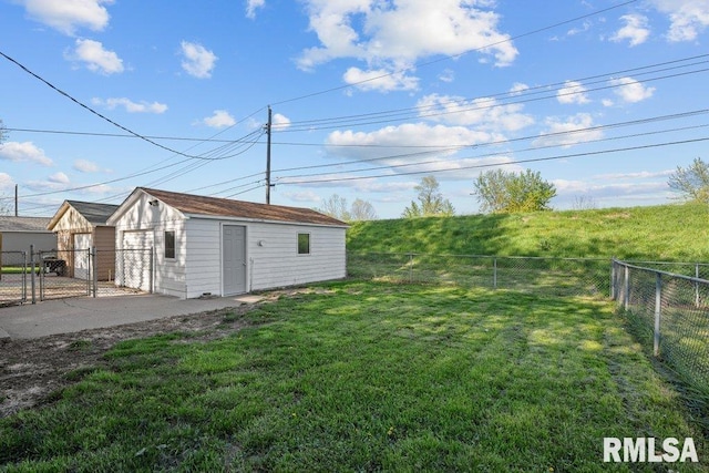 view of yard featuring a detached garage, a gate, an outbuilding, and a fenced backyard