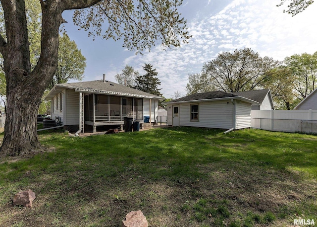 rear view of house with fence, a yard, and a sunroom