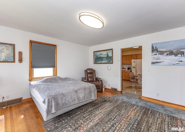 bedroom with baseboards, visible vents, and light wood-type flooring