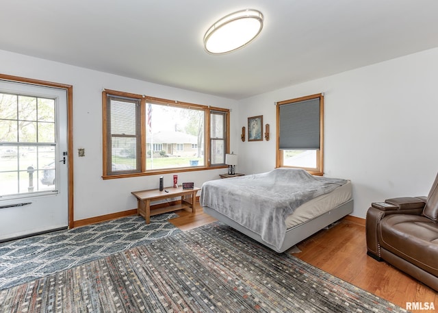 bedroom with baseboards, multiple windows, and wood finished floors
