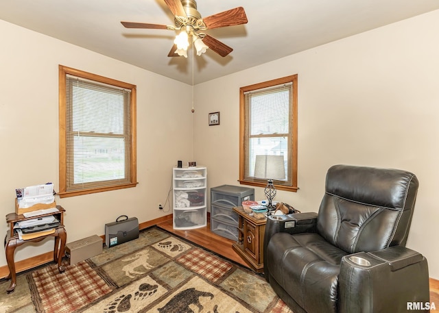 living area featuring baseboards, ceiling fan, and wood finished floors