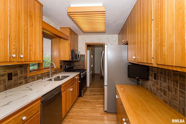 28018 230th St, Le Claire, IA 52753 - kitchen with decorative backsplash, brown cabinetry, appliances with stainless steel finishes, light wood-type flooring, and a sink