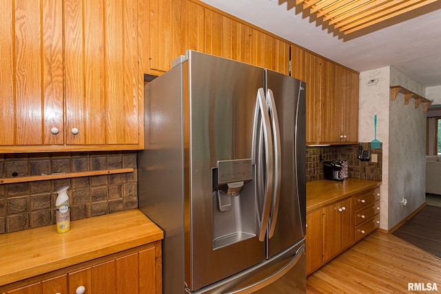 28018 230th St, Le Claire, IA 52753 - kitchen featuring stainless steel fridge, brown cabinetry, light wood-style flooring, wooden counters, and backsplash