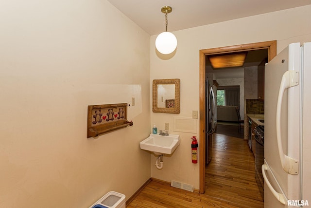 28018 230th St, Le Claire, IA 52753 - bathroom with visible vents, a sink, baseboards, and wood finished floors