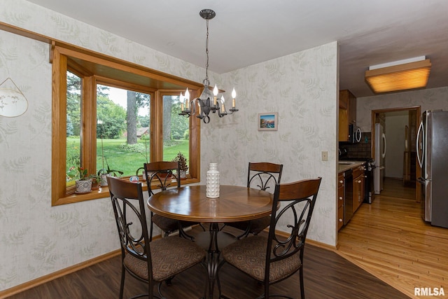 28018 230th St, Le Claire, IA 52753 - dining area with baseboards, wallpapered walls, light wood-style flooring, and a chandelier
