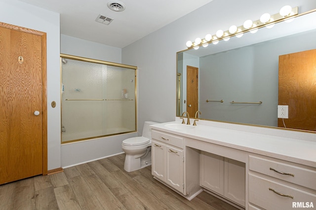 28018 230th St, Le Claire, IA 52753 - bathroom with visible vents, vanity, wood finished floors, toilet, and combined bath / shower with glass door