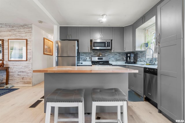 4012 172nd St N, East Moline, IL 61244 - kitchen featuring appliances with stainless steel finishes, light wood-type flooring, a sink, wood counters, and a breakfast bar