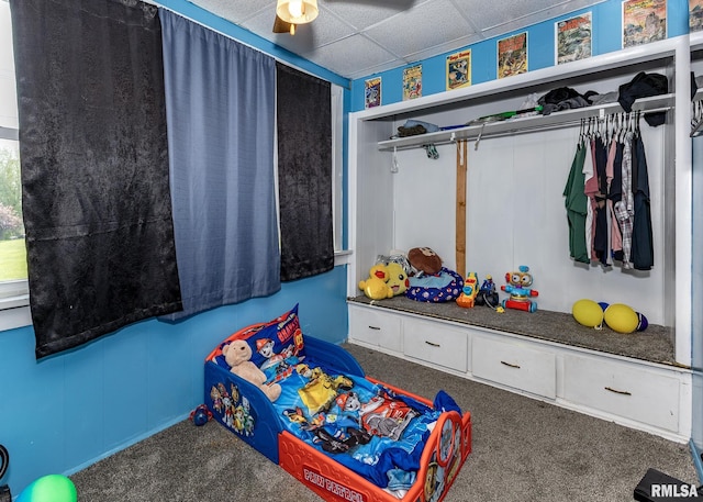 bedroom with carpet flooring, ceiling fan, a drop ceiling, and a closet