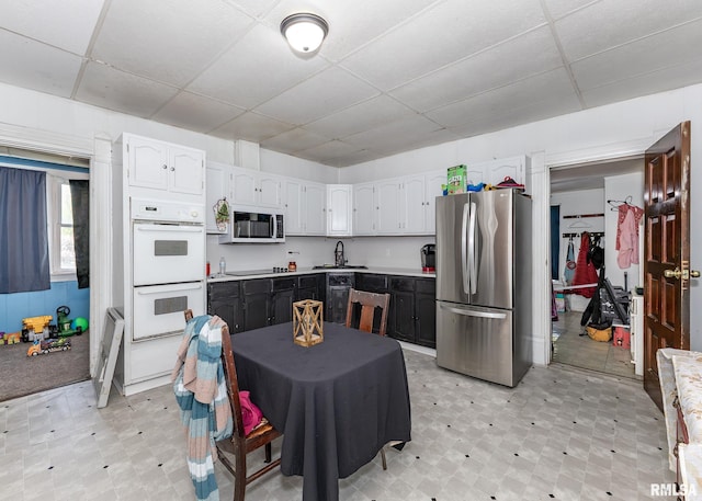 kitchen featuring freestanding refrigerator, light floors, a paneled ceiling, and double oven