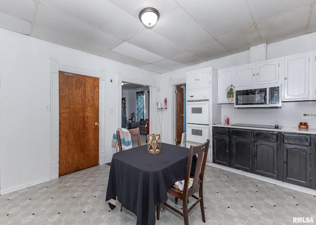 dining room with light floors, baseboards, and a drop ceiling