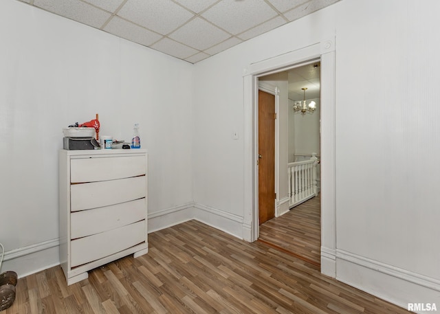 bedroom featuring baseboards, a paneled ceiling, and wood finished floors