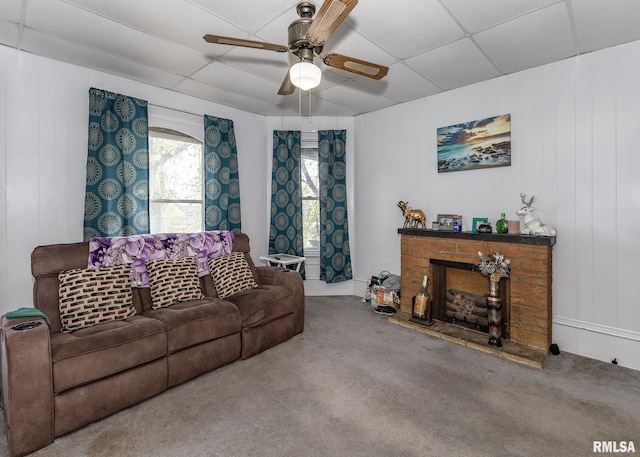 living room with carpet floors, a fireplace with raised hearth, and ceiling fan