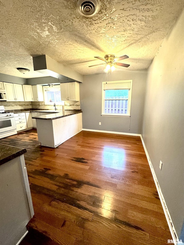 1001 W 6th St, West Frankfort, IL 62896 - kitchen featuring white cabinets, dark countertops, white appliances, a peninsula, and dark wood-type flooring