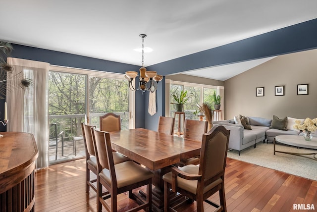 dining area with an inviting chandelier, hardwood / wood-style flooring, and lofted ceiling