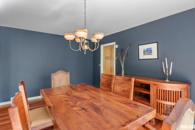 dining space featuring an inviting chandelier, baseboards, and wood finished floors