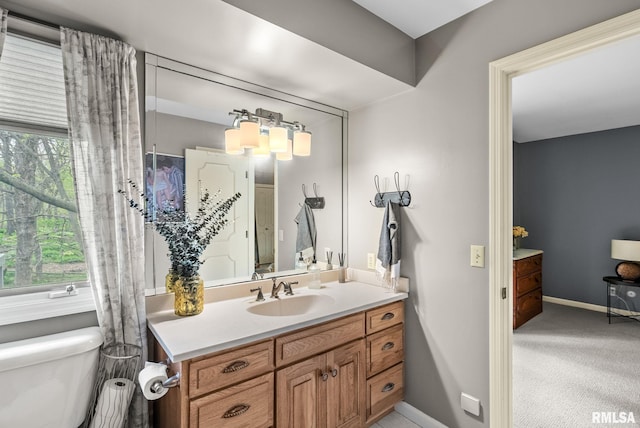 bathroom featuring toilet, baseboards, and vanity