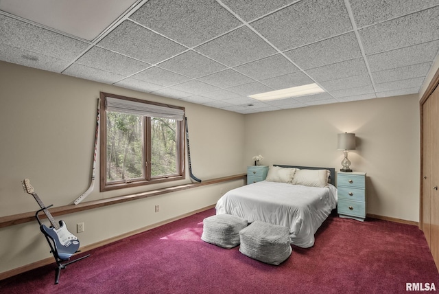 carpeted bedroom featuring baseboards and a paneled ceiling