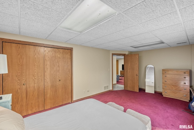 carpeted bedroom with baseboards, a closet, a paneled ceiling, and visible vents