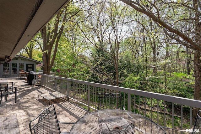 deck featuring a forest view and outdoor dining area