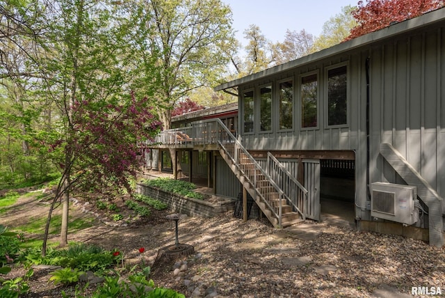 rear view of house featuring board and batten siding, stairway, and a deck