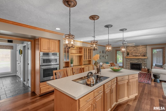 kitchen featuring a kitchen island, stainless steel double oven, a stone fireplace, light countertops, and black electric stovetop