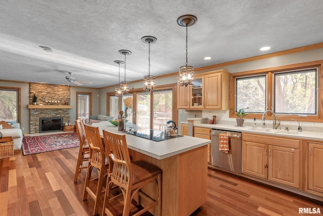 kitchen with a breakfast bar area, a center island, black electric cooktop, a sink, and dishwasher