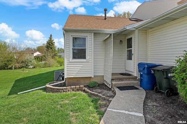 entrance to property with roof with shingles and a yard