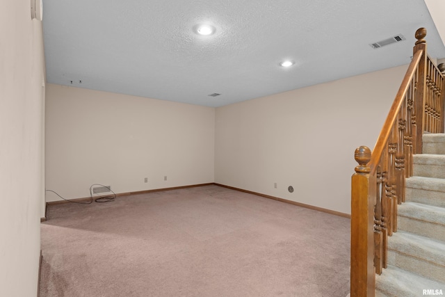 unfurnished room with light colored carpet, a textured ceiling, recessed lighting, visible vents, and stairway