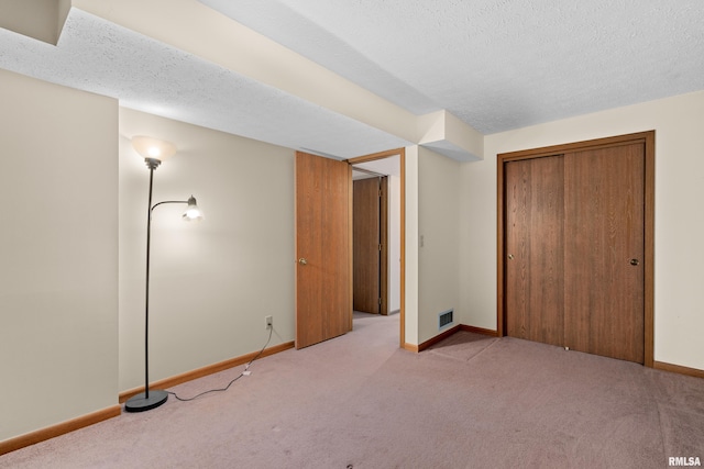 unfurnished bedroom featuring a textured ceiling, visible vents, baseboards, a closet, and carpet flooring