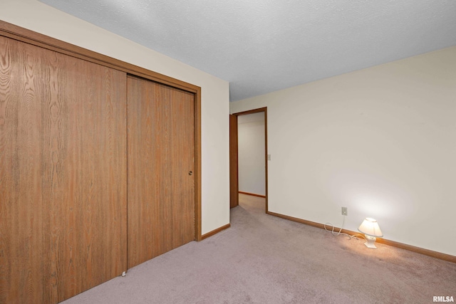 unfurnished bedroom featuring light colored carpet, baseboards, and a closet