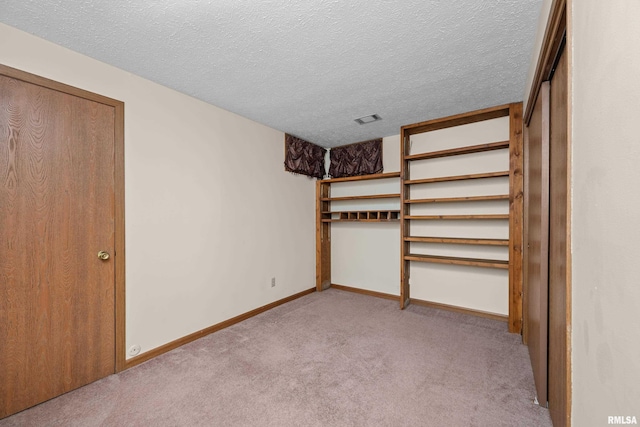 unfurnished bedroom featuring baseboards, visible vents, a textured ceiling, and light colored carpet