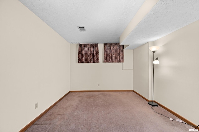 spare room featuring baseboards, carpet, a textured ceiling, and visible vents