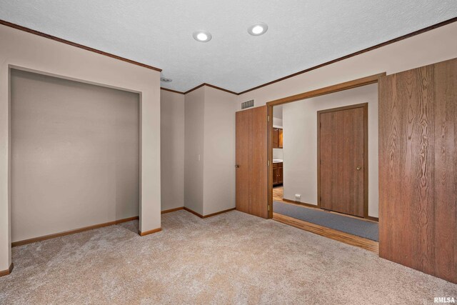 unfurnished bedroom with light colored carpet, ornamental molding, a textured ceiling, and visible vents