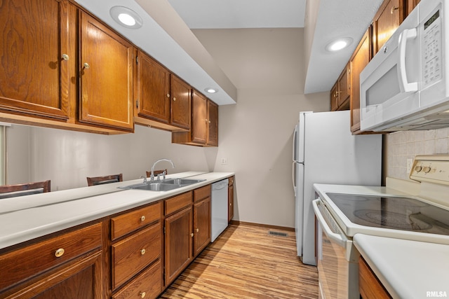 kitchen featuring decorative backsplash, white appliances, recessed lighting, light countertops, and a sink