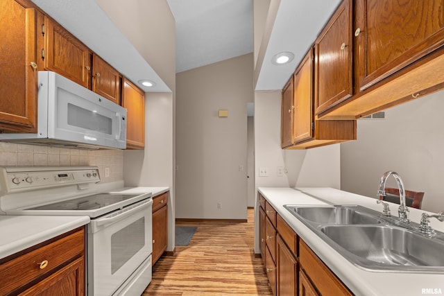 kitchen featuring white appliances, light countertops, a sink, and light wood-style floors