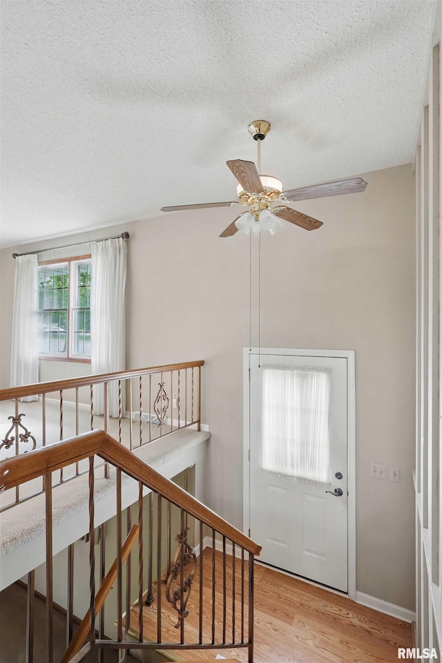 interior space featuring a textured ceiling, ceiling fan, and wood finished floors