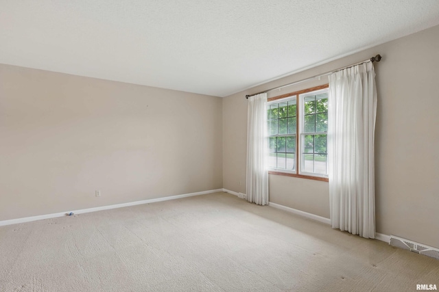 spare room with baseboards, visible vents, and light carpet