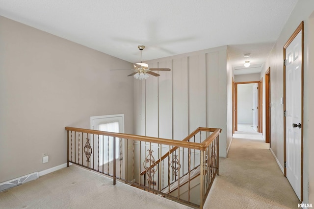 hall featuring carpet floors, baseboards, visible vents, and an upstairs landing