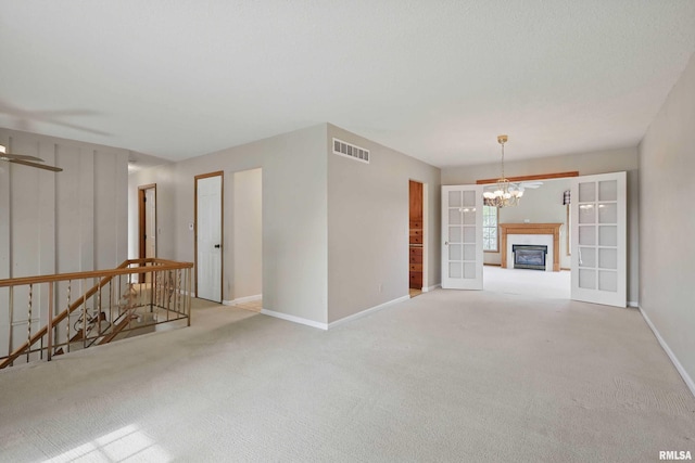 spare room featuring a notable chandelier, visible vents, baseboards, and carpet