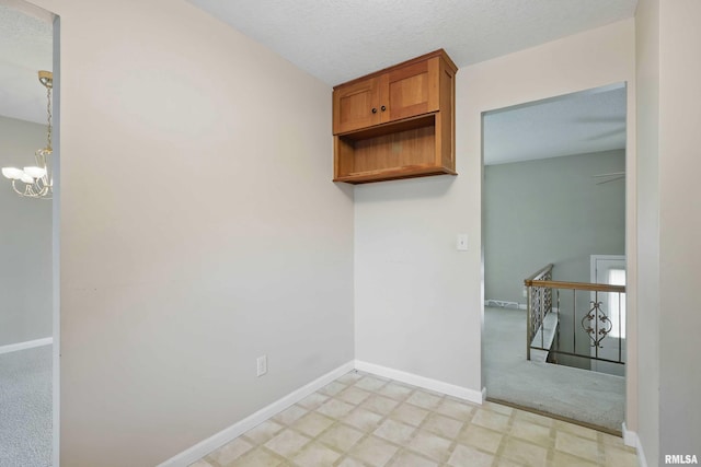 interior space featuring baseboards, brown cabinetry, light floors, and a chandelier