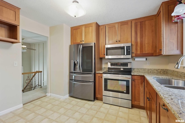 kitchen with a sink, light floors, brown cabinetry, and stainless steel appliances